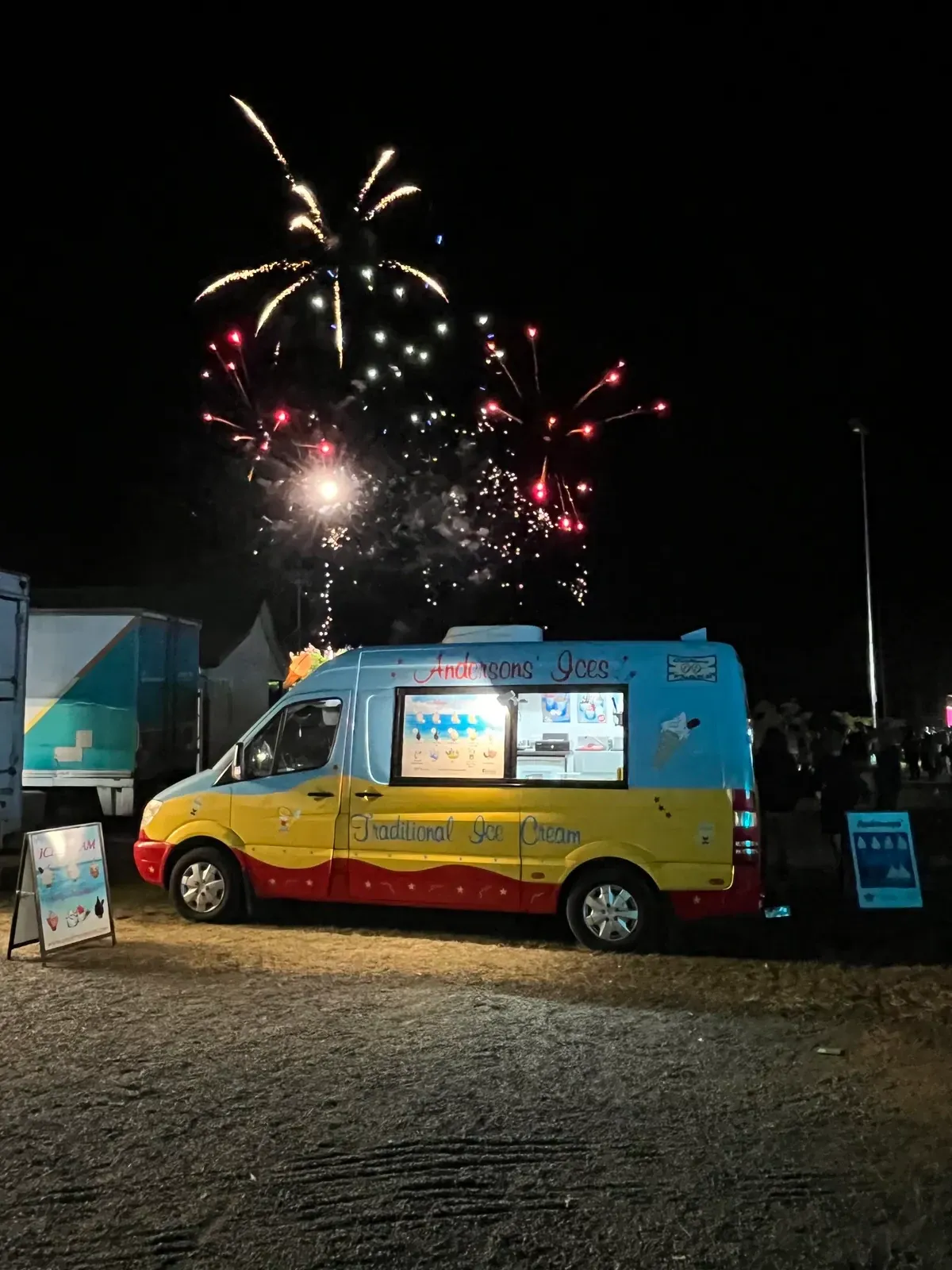The Andersons' Ices ice cream van lit up under fireworks at a night-time Gold Coast community event