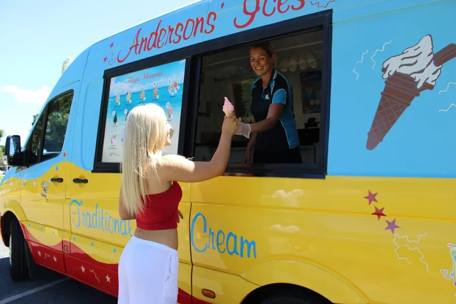 Taking a soft serve cone from the window of the Andersons' Ices ice cream truck, Gold Coast, 2026